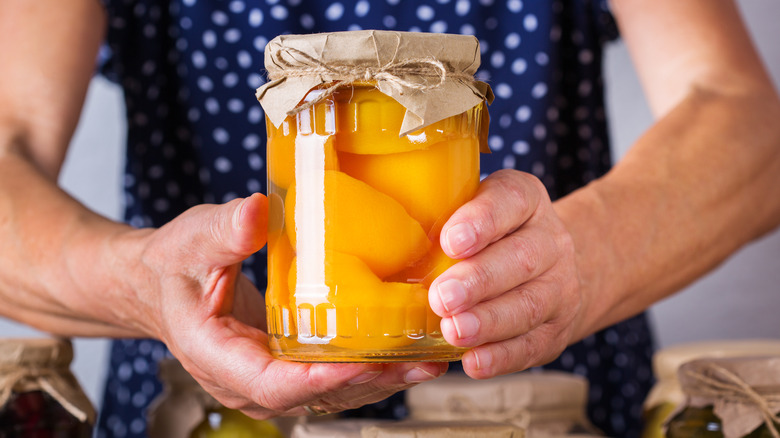 Hands holding jar of peaches