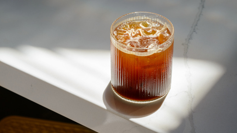 Glass of iced coffee on white table