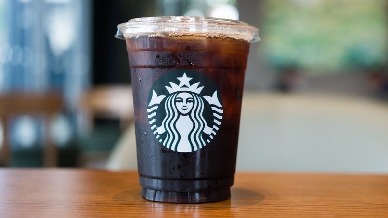 Tall Starbucks cold cup full of cold brew on wooden table