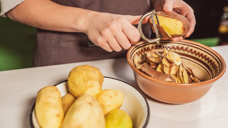 Person peeling potatoes into bowl