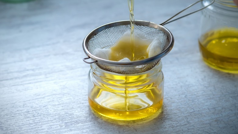 Straining bacon grease in a jar