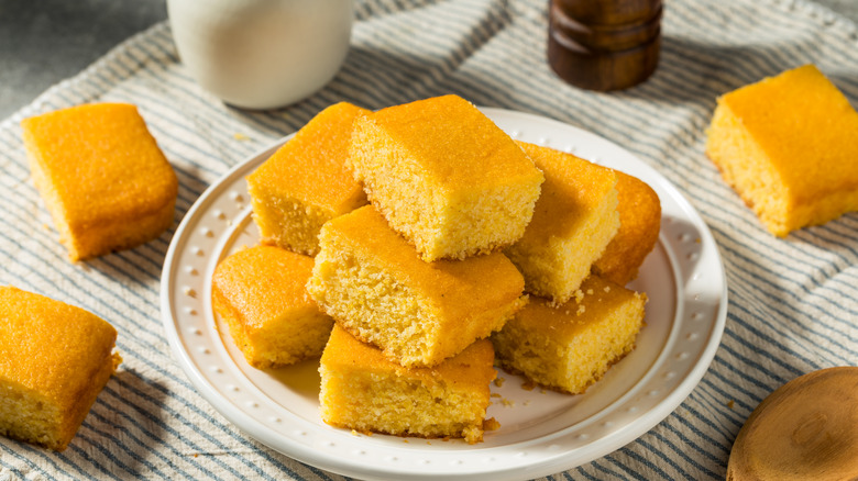 Sliced cornbread on a white plate on top of a striped tablecloth