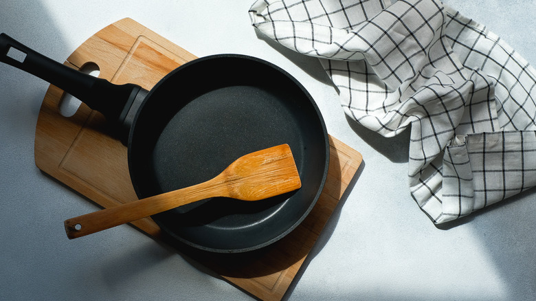 Cast iron skillet with wooden spatula sitting atop wooden cutting board