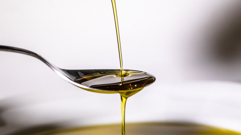 oil being poured onto silver spoonl