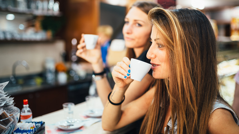 women drinking espressos at counter