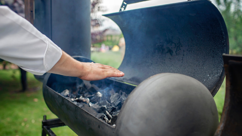 Hand over smoking grill