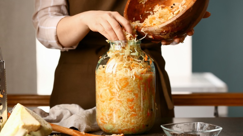 cook stuffing a jar with sauerkraut