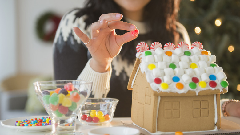 Person putting candy on a gingerbread house