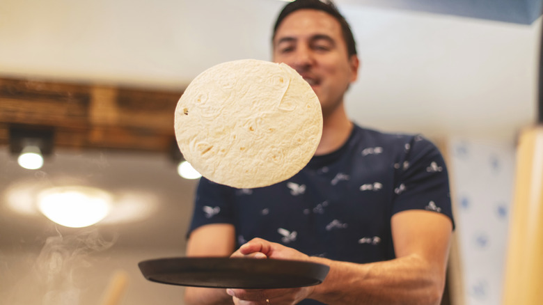 Person flipping tortilla in pan