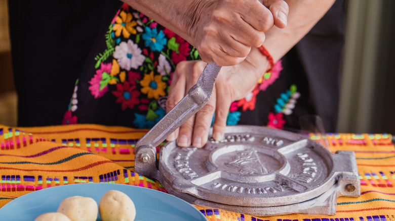 Person pressing tortillas on table