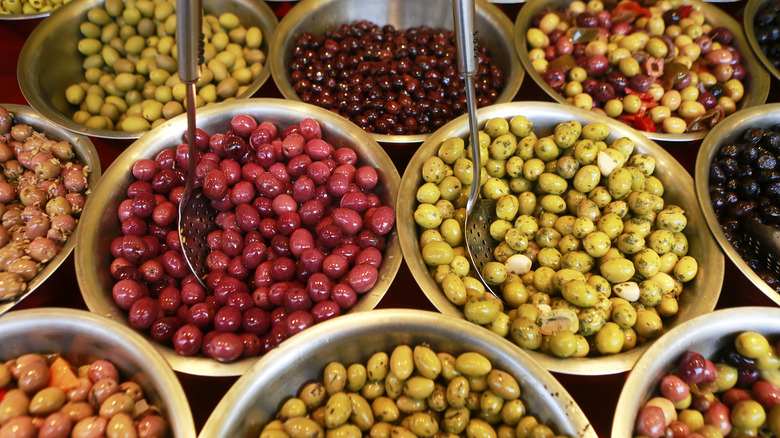 Big bowls of different colored olives at a market booth