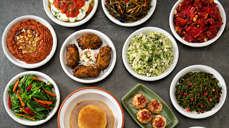 Top view of assorted colorful mezze dishes in white plates on a gray background