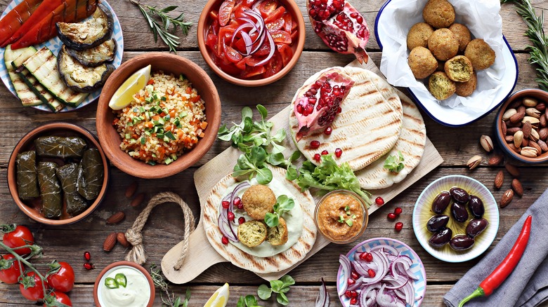 Beautiful mezze spread with multiple dishes and garnishes assembled in various plates on a wooden table