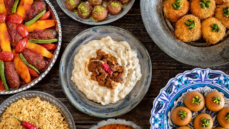 Top view of a colorful and varied mezze spread that includes sweet treats like baklava and knafeh