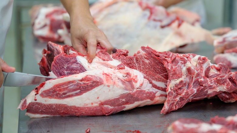 Person trimming beef with knife