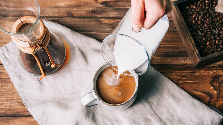 pouring creamer into coffee