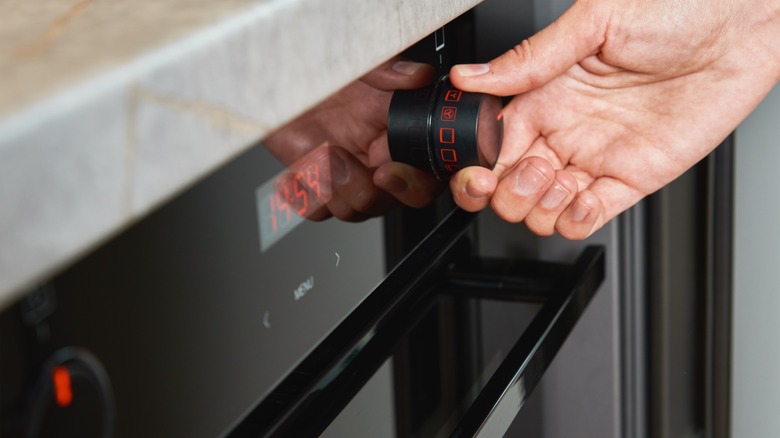 Woman adjusting oven temperature