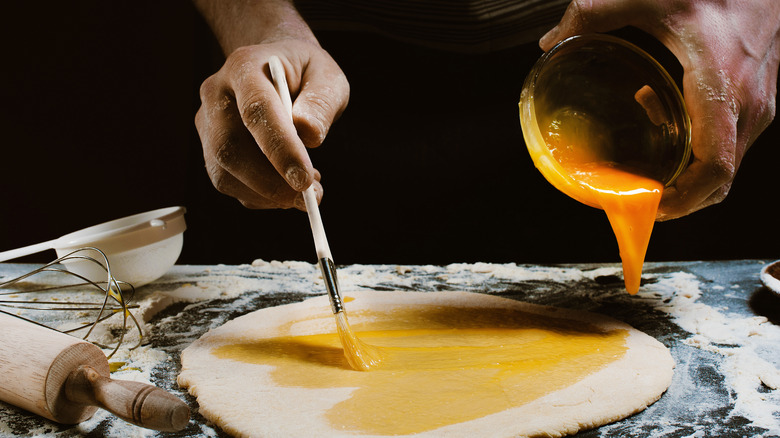 Person brushing egg on dough