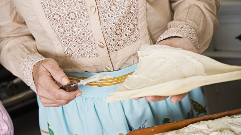 Hands filling tamale with masa