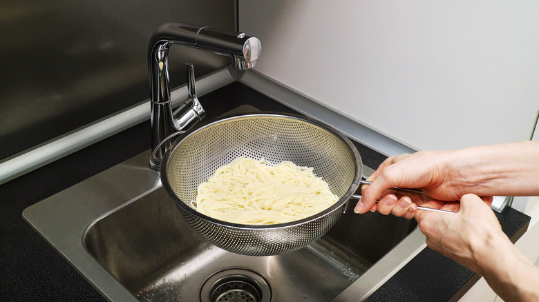 pasta draining in colander at sink