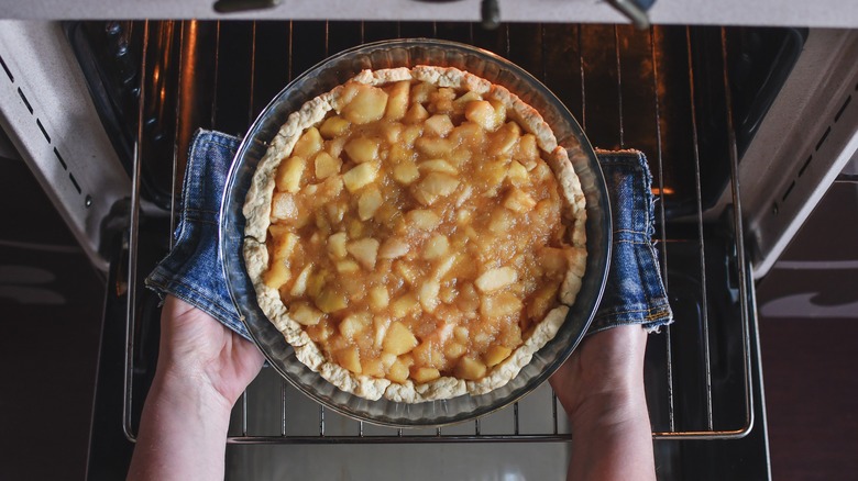 Pulling apple pie out of oven