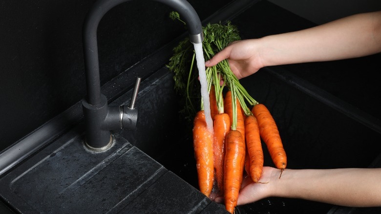 washing carrots in a sink