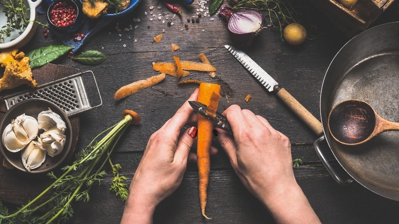 Woman peeling carrot on board