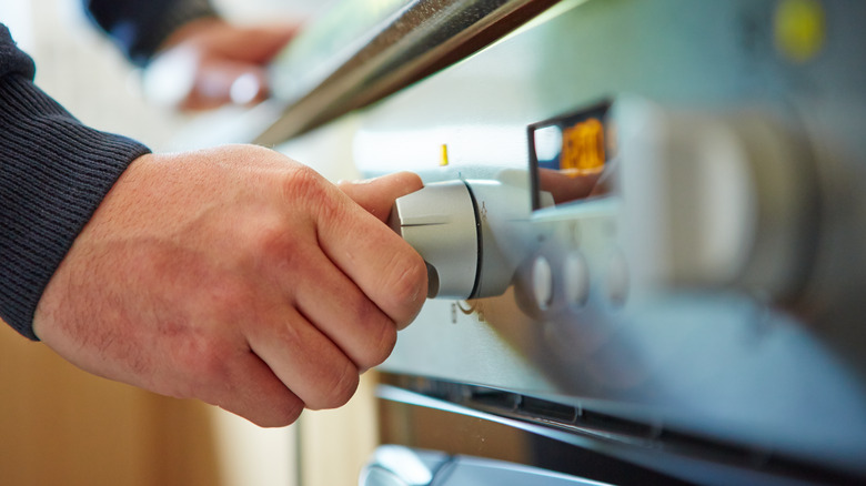 hand turning dial on oven