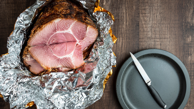ham in foil on wooden table