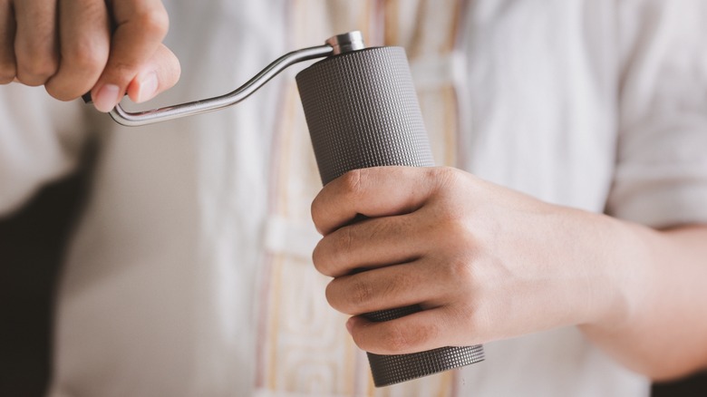 man using manual coffee grinder