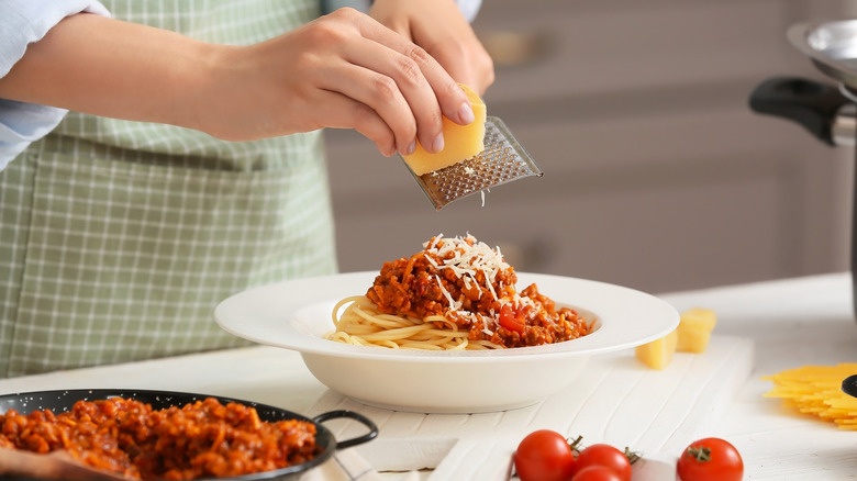 Grating parmesan over bolognese pasta