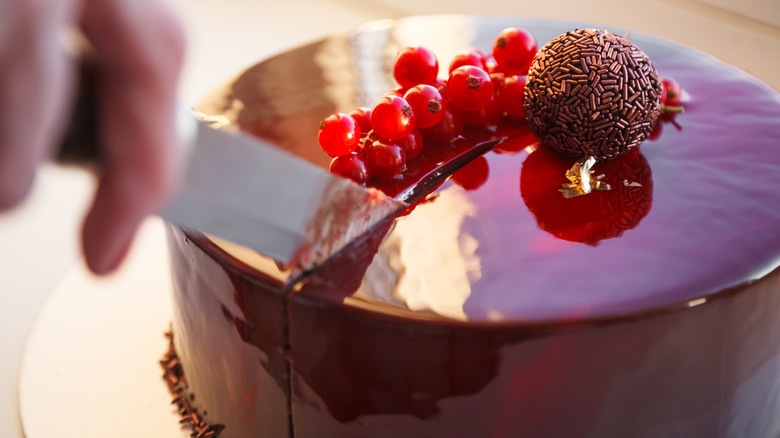 Person cutting mirror glaze cake