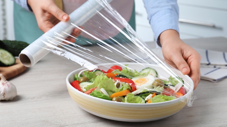 pulling plastic wrap over salad bowl