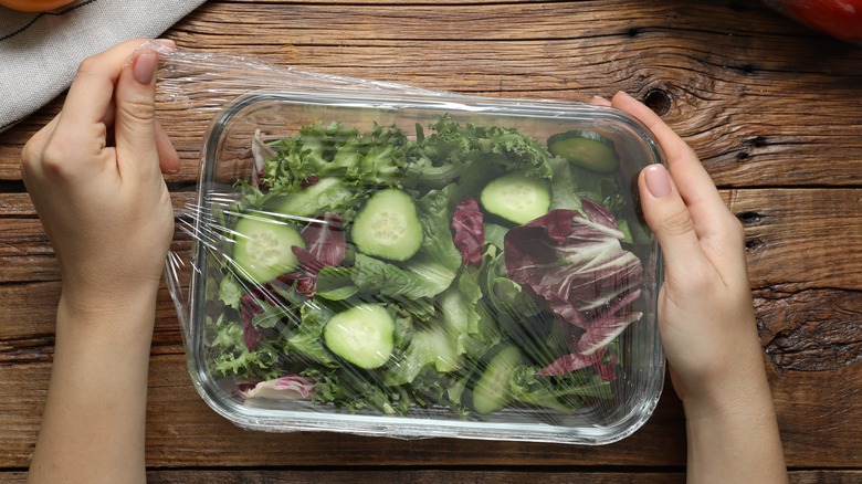 covering salad in glass dish with plastic wrap