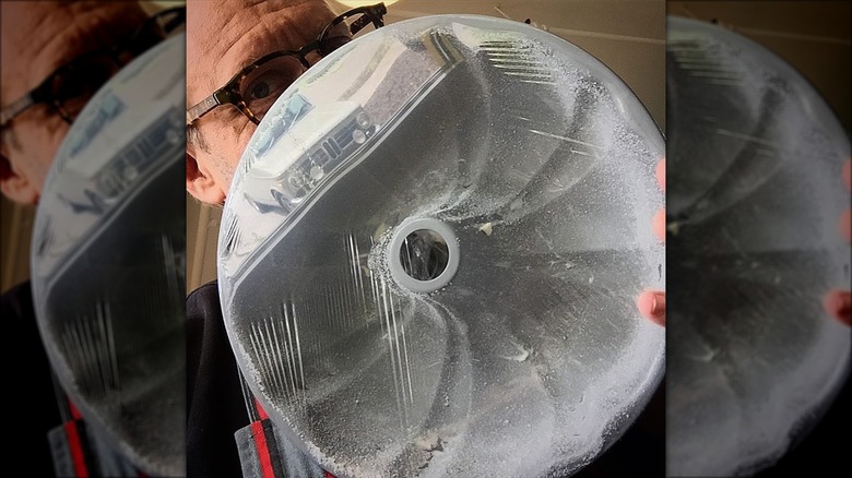 Alton Brown holding flour-coated cake pan wrapped in plastic