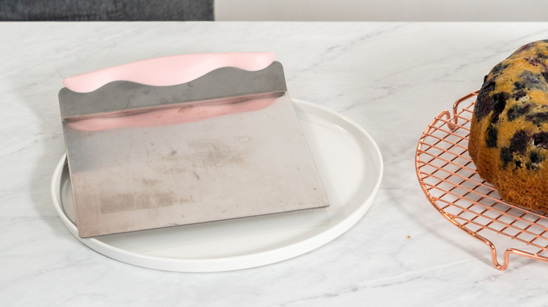 Cake lifter on a plate next to blueberry bundt cake