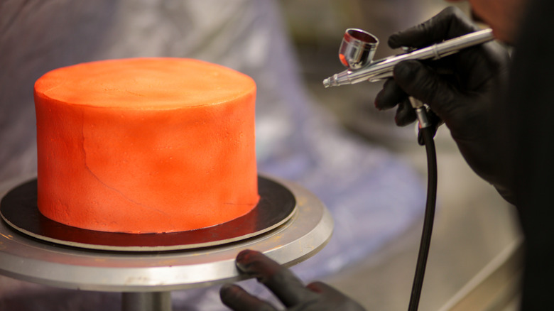 Using airbrushing machine on orange cake