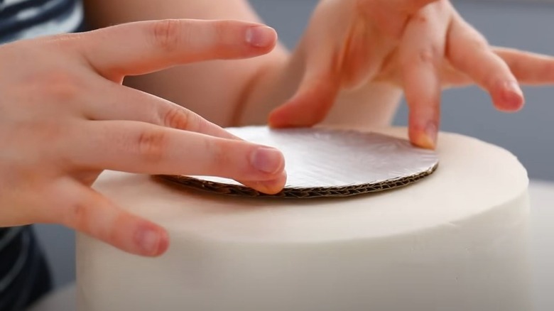 Placing a cardboard cake board on top of a cake tier