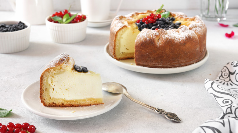 Kasekuchen slice on plate with berry cheesecake in the background