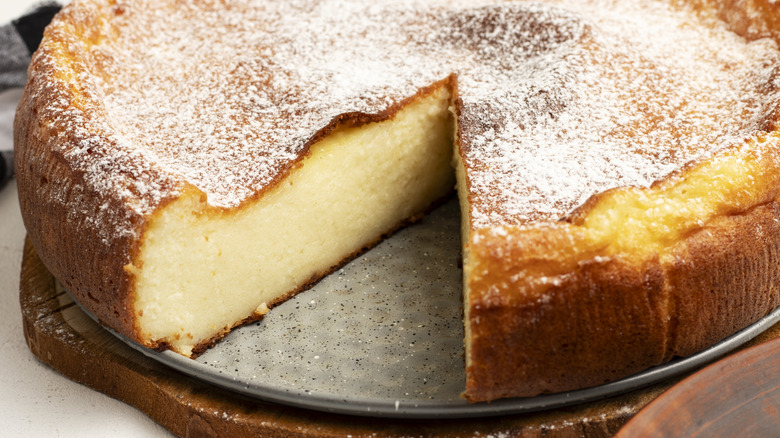 Ricotta cheesecake on plate with brown crust and dusting of powdered sugar