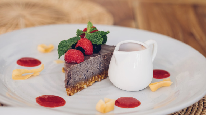 Raw cheesecake on plate with berry and mint garnish