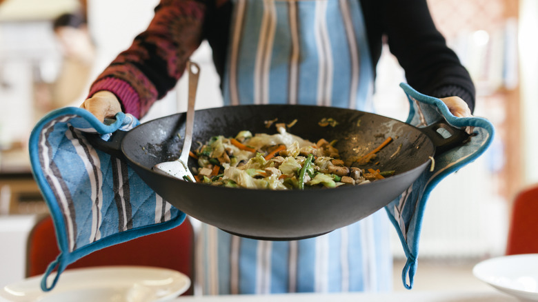 Person holding wok of stir fry