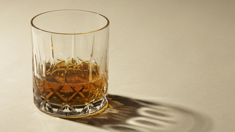 Golden-colored bourbon in a clear glass with a beige background