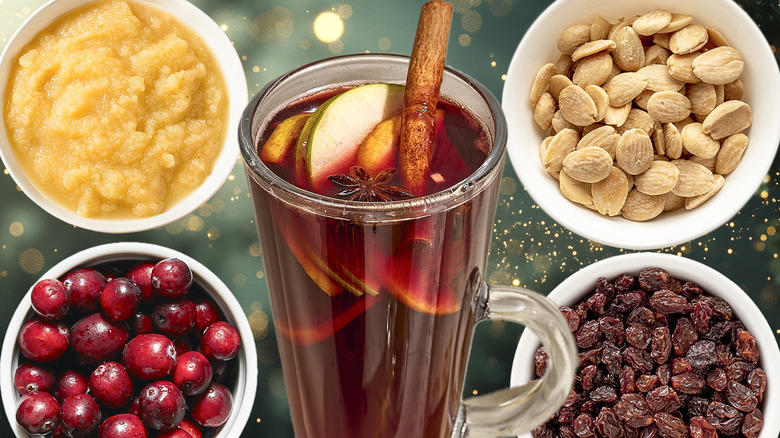 a tall, glass mug filled with mulled wine, citrus, cinnamon, anise, and fruit surrounded by bowls of fresh cranberries, applesauce, nuts, and raisins with various add-ins