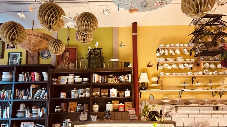 Bookshelf and shelves with teacups behind counter