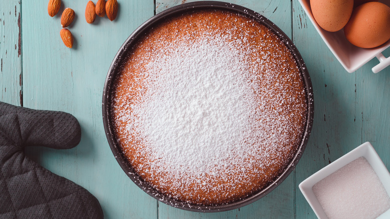 almond cake on blue table with oven mitt and eggs