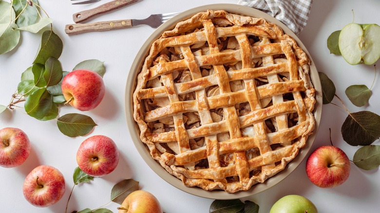 lattice-top apple pie surrounded by apples