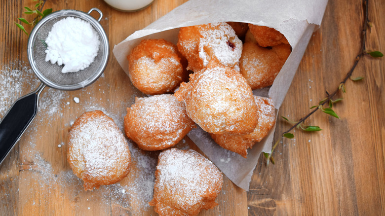 cala tout chaud rice fritters dusted with powdered sugar and wrapped in parchment paper