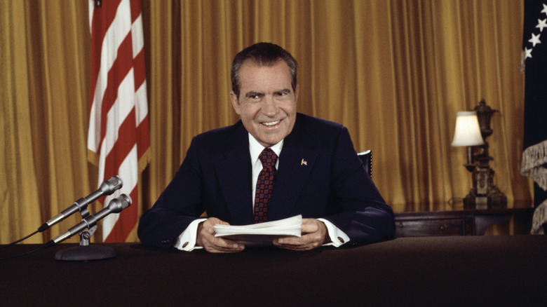 President Nixon smiling while holding papers after a televised address