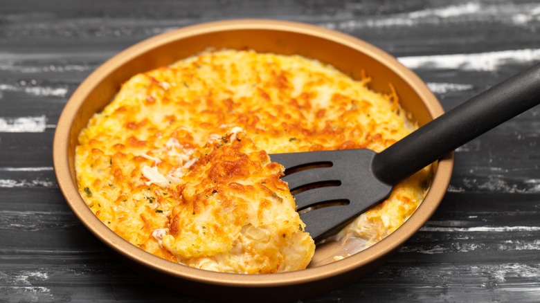 Black spatula serving baked fish and cheese